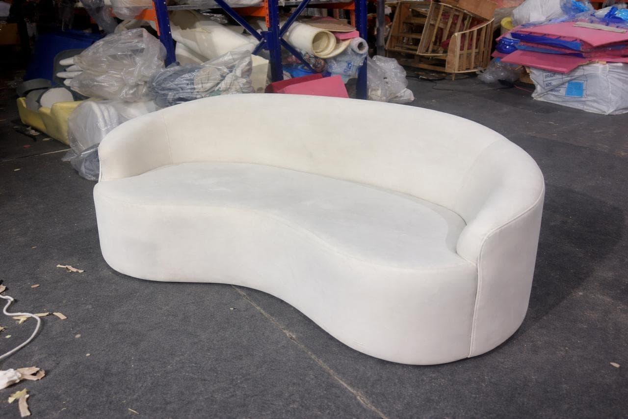 A white, curved sofa with a continuous backrest and seat, exhibiting a contemporary design. The piece has soft, rounded edges and appears to be upholstered. — 3D model