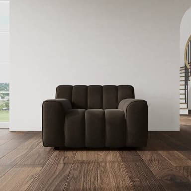 A single-seater armchair upholstered in dark brown fabric, featuring prominent vertical channel tufting on the backrest and seat. It has wide, rounded armrests and a plush, low-profile silhouette. — 3D model