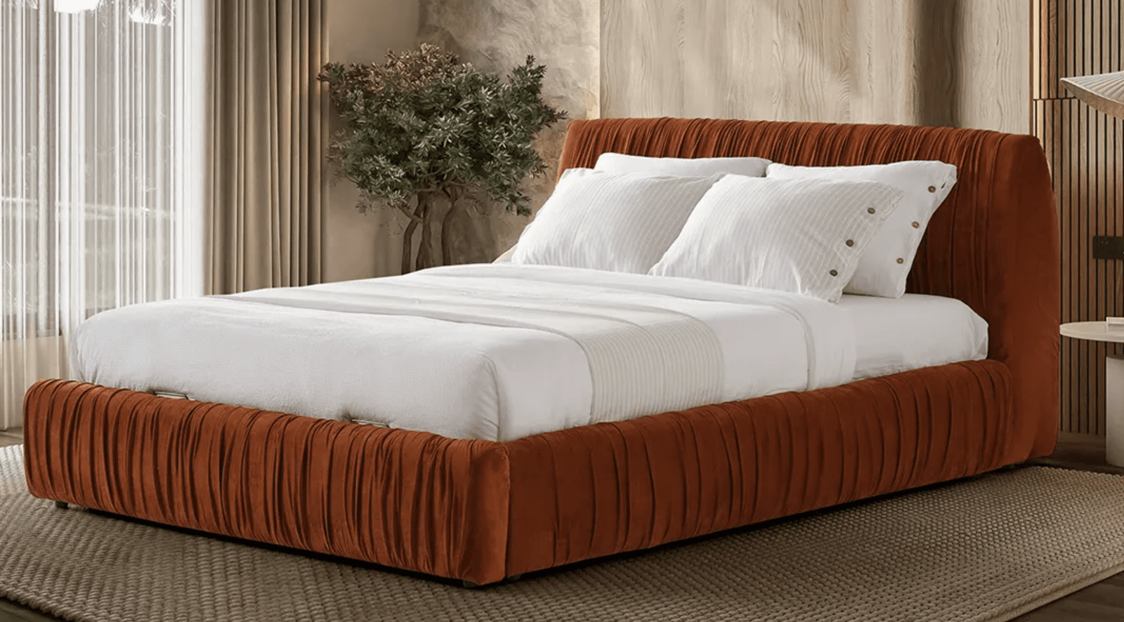 A modern platform bed frame upholstered in a rust-colored, velvet-like fabric with a distinctive pleated texture on the headboard and side rails. The bed is dressed with white linens and pillows. — 3D model