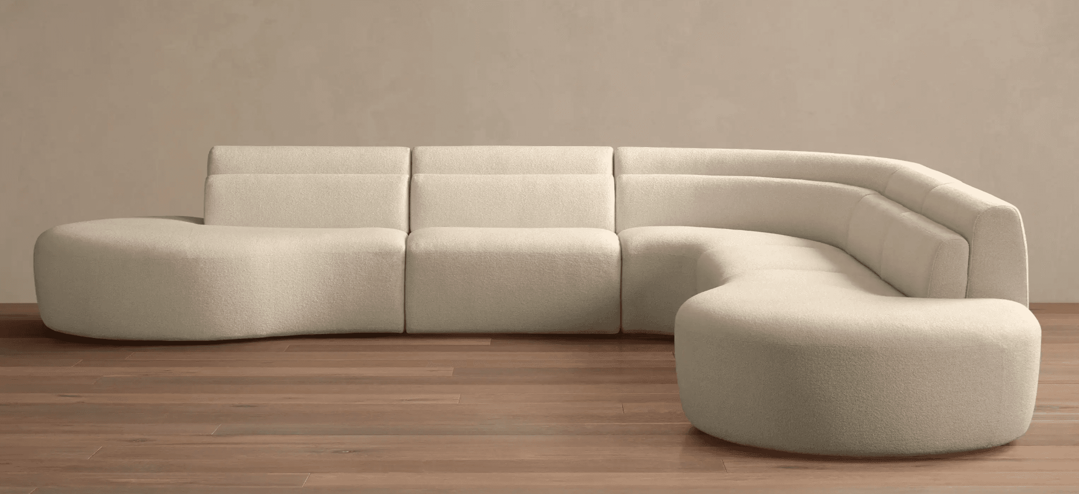 A modular sectional sofa with a curved, organic design. It is upholstered in a textured fabric and comprises several distinct modules that form a cohesive seating arrangement. The sofa features rounded armrests and a low profile. The back cushions have subtle horizontal tufting. — 3D model