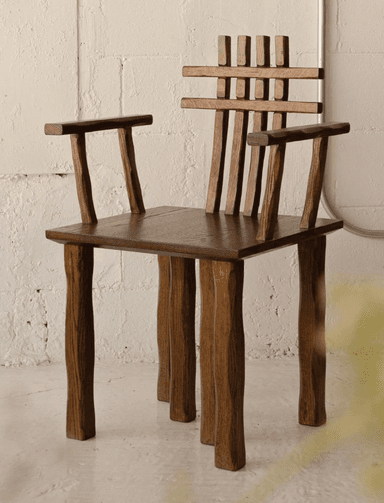 A robust, rustic armchair crafted from dark-stained wood, featuring a distinctive slatted backrest with both vertical and horizontal elements. The chair has a square, solid seat and integrated armrests. Its sturdy, straight legs contribute to its durable appearance, and the visible grain suggests solid wood construction. — 3D model