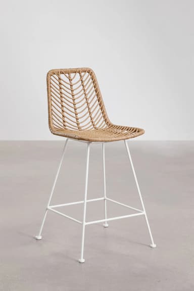 A tall bar stool featuring a woven natural rattan seat and backrest, supported by a white powder-coated metal frame. The frame includes crossbars that serve as a footrest. — 3D model