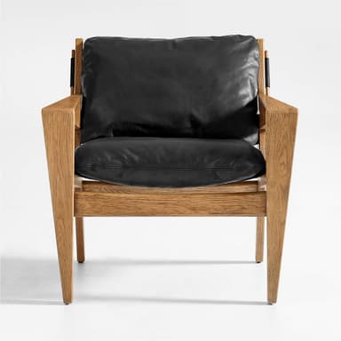 A modern armchair with a solid wood frame and black leather cushions. The frame features a clean, angular design with visible wood grain. Black leather straps are integrated into the sides of the frame, connecting the seat and back support elements. The armchair includes a plush seat cushion and a separate back cushion. — 3D model