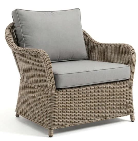 A light brown wicker armchair with light gray cushions. The armchair features a woven rattan or wicker frame with rounded arms and a high back. It includes a seat cushion and a back cushion, both upholstered in a plain, light gray fabric with piped edges. The armchair has four short, tapered legs. — 3D model