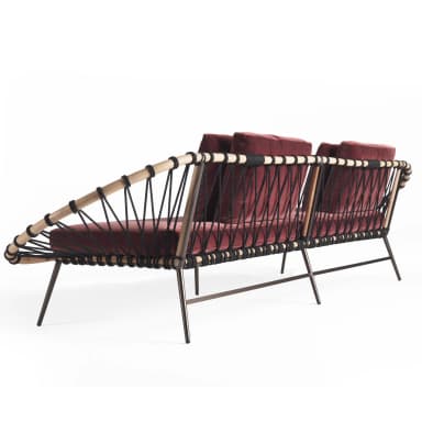 A contemporary sofa featuring a distinctive design with a woven backrest and armrest on one side, and a more open structure on the other. The seating and back cushions are upholstered in a deep red velvet fabric. The frame appears to be constructed from wood or a wood-like material, with thin metal legs. The backrest is formed by a curved structure with interwoven black cords or ropes. — 3D model