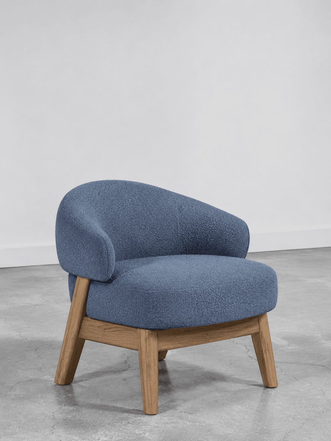 A single-seater chair featuring a rounded, continuous backrest and armrests, upholstered in a textured blue fabric, and supported by four splayed wooden legs. — 3D model