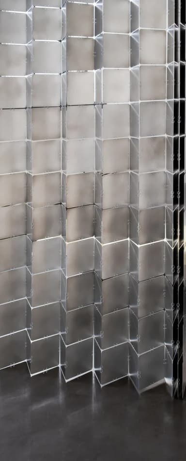 A room divider composed of multiple square, metallic panels arranged in a flexible, accordion-like structure. The panels are connected by visible fasteners, allowing them to fold and pivot. The surface reflects light, creating a shimmering, alternating pattern of light and dark squares. — 3D model