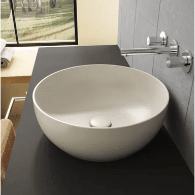 A modern circular vessel sink in a matte light greige finish, featuring gently sloped interior walls and a color-matched, integrated pop-up drain at its center. — 3D model