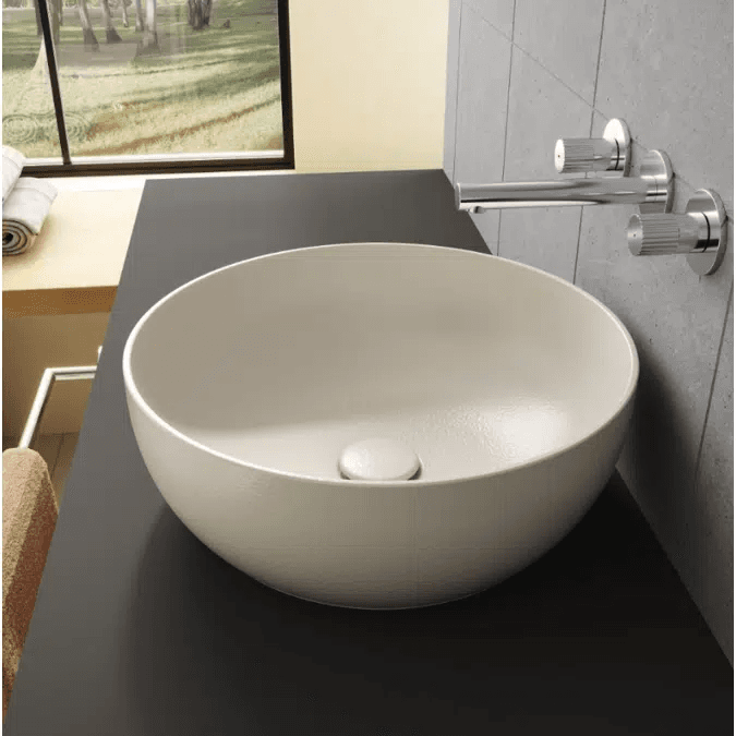 A modern circular vessel sink in a matte light greige finish, featuring gently sloped interior walls and a color-matched, integrated pop-up drain at its center. — 3D model