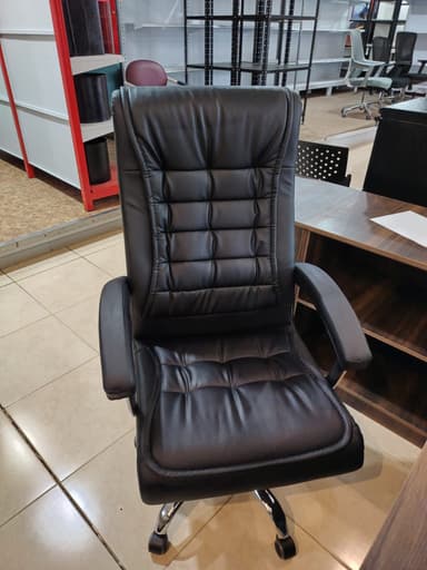 A contemporary high-back executive office chair featuring black tufted faux leather upholstery, padded armrests, and a five-star chrome-plated metal base with casters for mobility. — 3D model