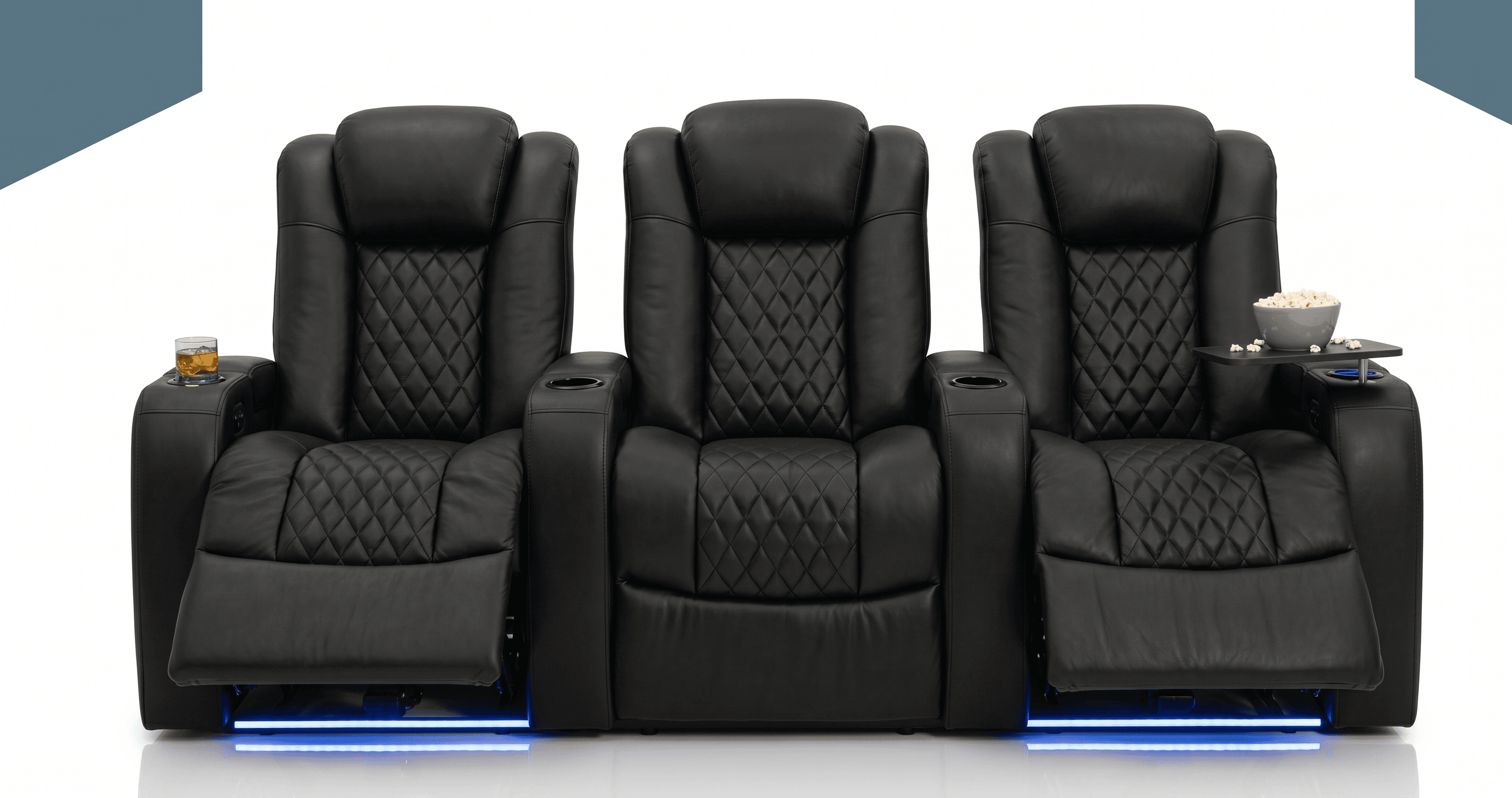 A set of three connected black leather recliners designed for home theater use. Each chair features diamond tufting on the seat and backrest, padded headrests, and integrated cup holders. The leftmost and rightmost chairs have a removable tray table attachment, with the rightmost one holding a bowl of popcorn. The recliners have illuminated blue LED lighting at the base, suggesting a modern aesthetic and functionality. — 3D model