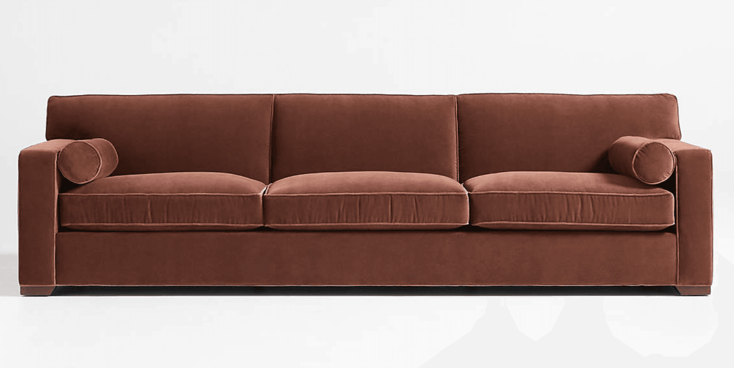 A modern three-seater sofa upholstered in a rust brown velvet-like fabric, featuring track arms, three seat cushions, three back cushions, and two round bolster pillows. — 3D model