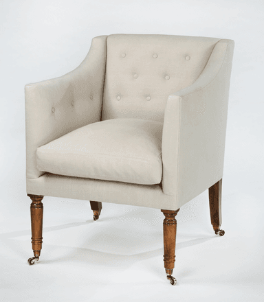 A tufted armchair with a high back and rolled arms, upholstered in a light-colored fabric. It features wooden legs with brass casters. — 3D model