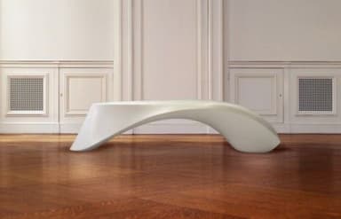 A contemporary white chaise lounge featuring a distinctly S-shaped, ergonomic design. The furniture piece is made from a single molded form, presenting a seamless and minimalist aesthetic. Its smooth, undulating curves are designed to support the body in a reclining position, typical of modern lounge seating. The surface has a matte finish, emphasizing its clean lines and simple elegance. — 3D model