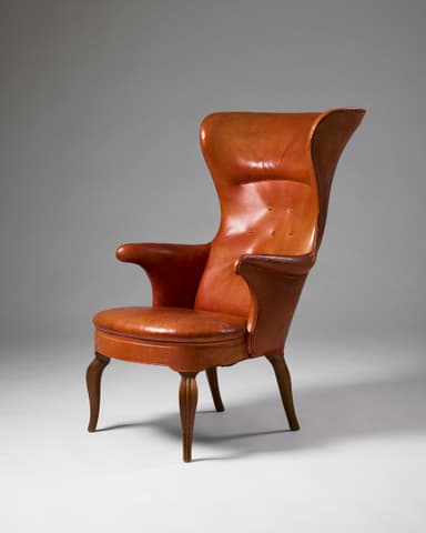 A high-backed wingback armchair upholstered in rich cognac-colored leather. The chair features a distinct winged design at the top of the backrest, offering an enveloping feel. The backrest is subtly button-tufted, and the seat cushion appears well-padded. It rests on four slender, gently curved wooden legs, visible below the upholstered frame. — 3D model