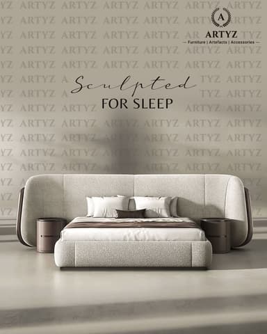A modern bed frame with an integrated headboard and two bedside tables. The headboard is upholstered in a textured light-colored fabric and curves outwards on the sides. The bed frame is also upholstered in the same fabric. Two cylindrical bedside tables with a dark wood finish and recessed handles are attached to the sides of the headboard. The bed is made up with white linens, accent pillows, and a brown throw blanket. — 3D model