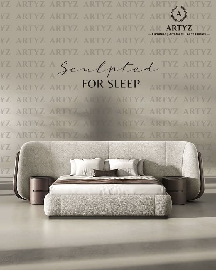 A modern bed frame with an integrated headboard and two bedside tables. The headboard is upholstered in a textured light-colored fabric and curves outwards on the sides. The bed frame is also upholstered in the same fabric. Two cylindrical bedside tables with a dark wood finish and recessed handles are attached to the sides of the headboard. The bed is made up with white linens, accent pillows, and a brown throw blanket. — 3D model