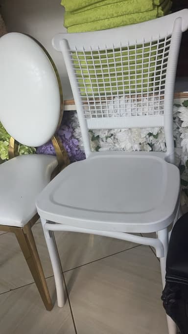 A white, single-piece molded plastic chair featuring a distinct open-weave pattern on its backrest, mimicking traditional wicker or rattan. The chair has a solid seat and subtly curved legs, suggesting a contemporary and lightweight design suitable for various settings. — 3D model