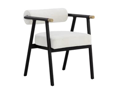 A contemporary armchair featuring a dark, possibly black-stained, wooden frame with clean lines. The seat and cylindrical backrest are upholstered in a light, textured fabric, resembling bouclé or a similar weave. The armrests are an extension of the frame, culminating in subtle brass-finished accents on the outer edges. The chair's design combines minimalist aesthetics with comfortable padding, suitable for various modern interiors. — 3D model