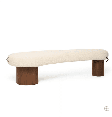 A modern bench featuring an organically shaped, off-white bouclé upholstered seat supported by two sturdy, cylindrical dark wood legs. — 3D model