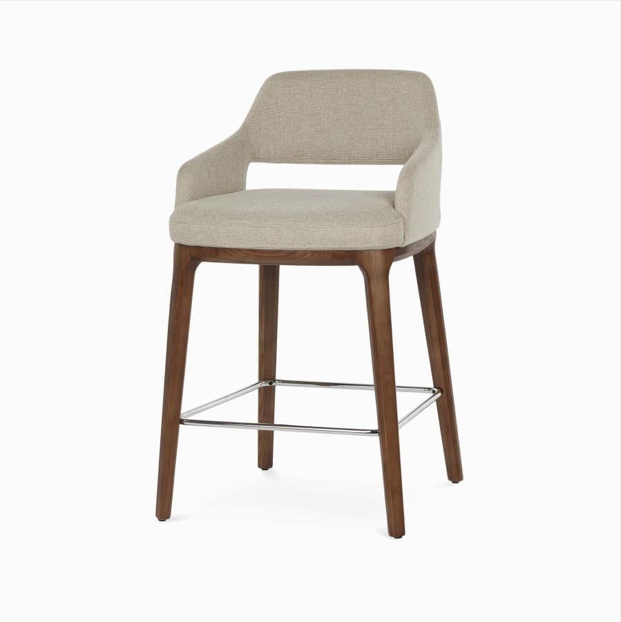A contemporary bar stool with upholstered seating and backrest, supported by a wooden frame and legs. It features integrated armrests and a metal footrest. — 3D model