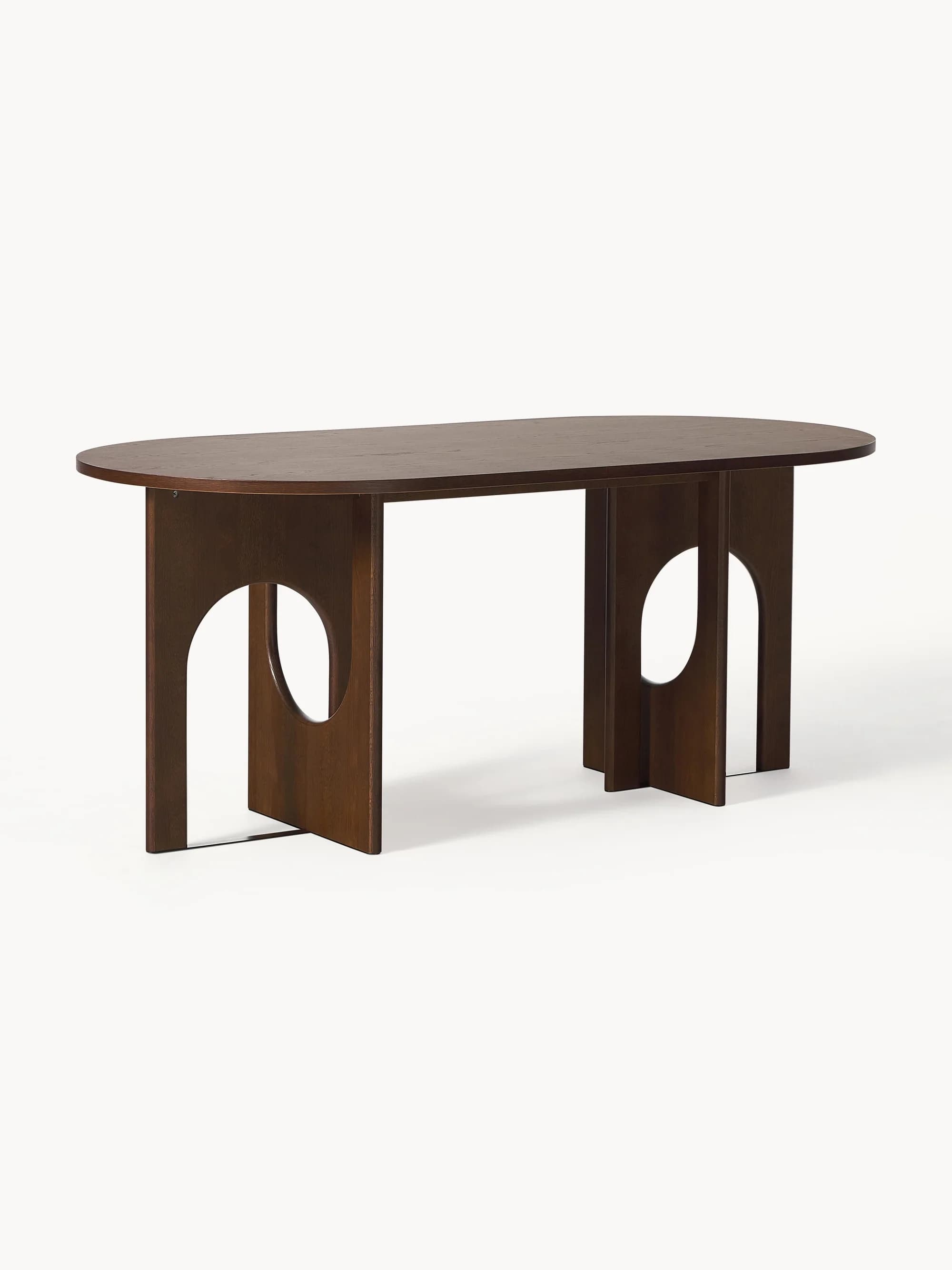 An oval-shaped dining table with a dark wood finish. The table features a thick, solid tabletop and two substantial, abstract pedestal bases. Each base is constructed from vertical wooden panels with large, cut-out arch shapes, giving it a sculptural and contemporary aesthetic. The legs appear to be cross-braced at the bottom for stability. — 3D model