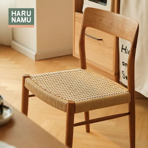 An armless dining chair constructed from light-toned natural wood, featuring a curved backrest and a square seat upholstered with woven rattan. The chair has a minimalist design with a visible wood grain and simple, sturdy legs. — 3D model