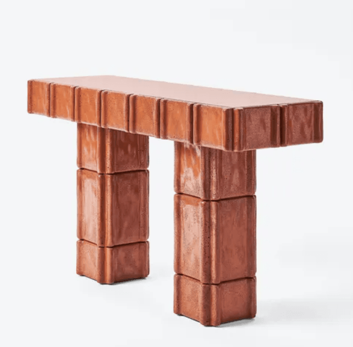 A bench constructed from reddish-brown, possibly terracotta or concrete, modular blocks. The top surface and the two supporting legs are composed of these fluted, rectangular units, creating a distinctive textured and robust appearance. — 3D model