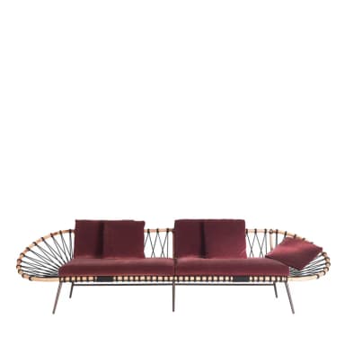 A contemporary sofa featuring a distinctive design with a woven backrest and armrest on one side, and a more open structure on the other. The seating and back cushions are upholstered in a deep red velvet fabric. The frame appears to be constructed from wood or a wood-like material, with thin metal legs. The backrest is formed by a curved structure with interwoven black cords or ropes. — 3D model