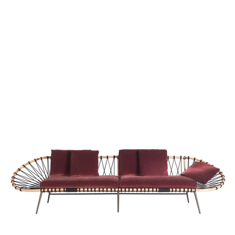 A contemporary sofa featuring a distinctive design with a woven backrest and armrest on one side, and a more open structure on the other. The seating and back cushions are upholstered in a deep red velvet fabric. The frame appears to be constructed from wood or a wood-like material, with thin metal legs. The backrest is formed by a curved structure with interwoven black cords or ropes. — 3D model
