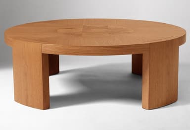 A round, low-profile coffee table constructed from natural oak wood. The tabletop features a subtle veneered pattern created by contrasting wood grain directions. It is supported by three thick, rectangular block legs that are seamlessly integrated into the underside of the tabletop, giving it a sturdy and grounded appearance. The overall aesthetic is modern and minimalist with clean lines. — 3D model