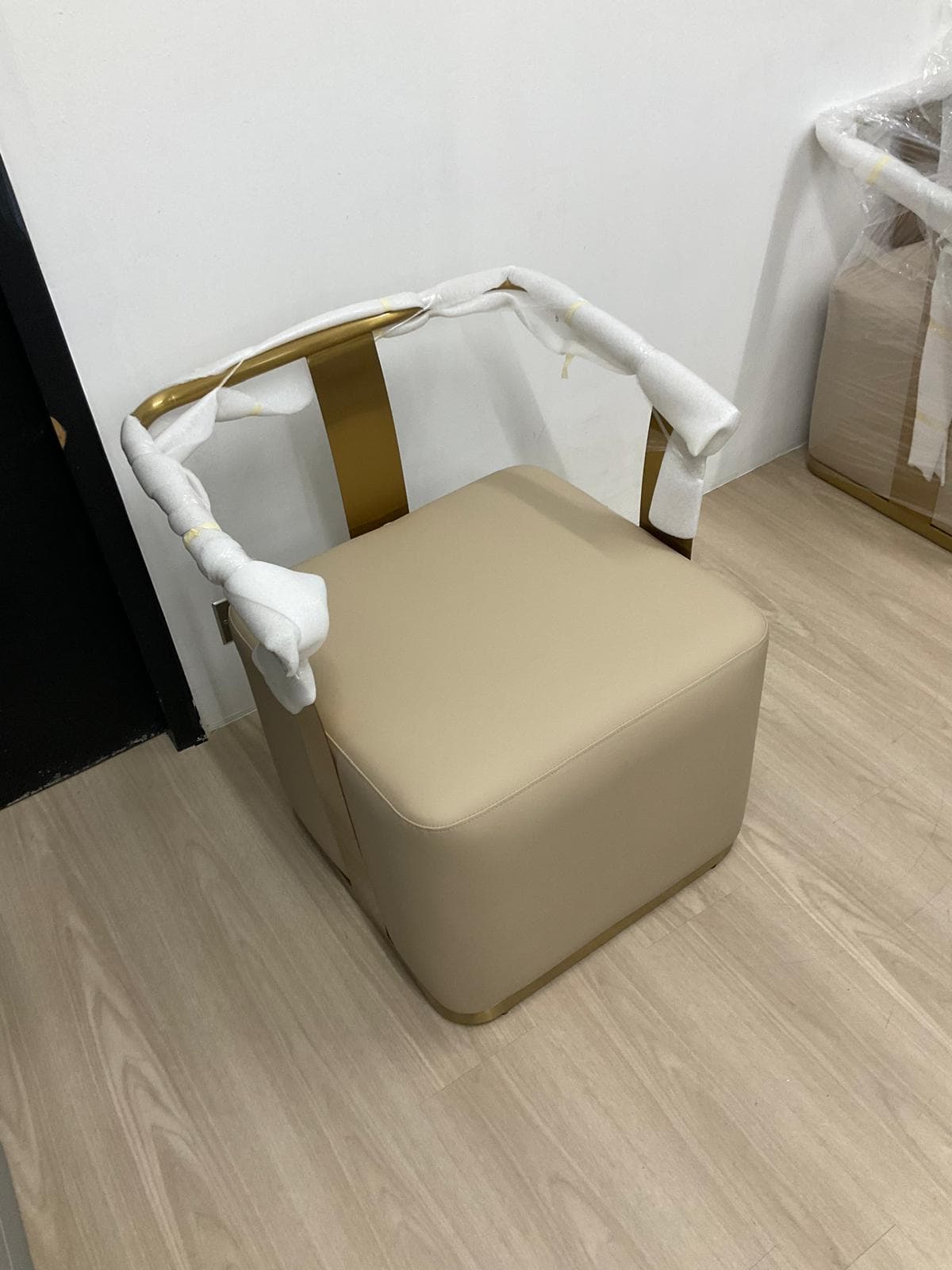 A compact, modern accent chair featuring a square, cream-colored upholstered seat and back. The defining element is a U-shaped brass-toned metal frame that serves as integrated armrests and wraps around to support the low backrest. The chair has a sleek, minimalist aesthetic. — 3D model