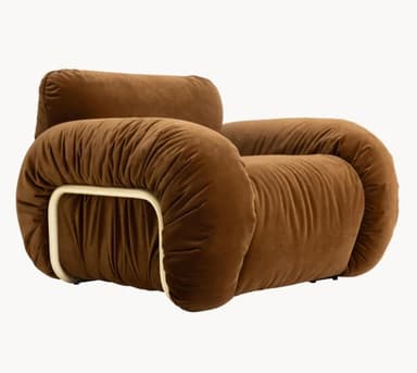 A plush, sculptural armchair upholstered in a rich brown velvet fabric. The armchair features an organic, rounded silhouette with ample cushioning that appears to be gathered or shirred, creating a textured effect. A tubular metal frame, finished in a light, possibly cream or off-white color, is visible beneath the upholstery, providing structural support and a contrasting element. The design evokes a contemporary, possibly retro-inspired aesthetic. — 3D model