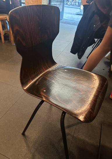 A modern side chair featuring a curved, dark wood grain molded plywood seat and back, supported by four splayed black metal legs. — 3D model