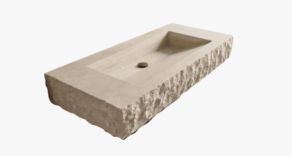 A rectangular stone sink with a rough-hewn exterior and a smooth, carved basin. The sink features a central drain with a dark, circular fitting. The material appears to be a natural stone with a light, creamy beige color and visible natural veining. — 3D model