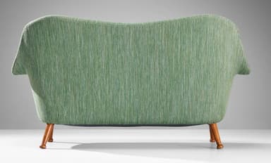 A two-seater sofa with a curvaceous backrest and armrests, upholstered in a textured green fabric. The sofa is supported by four tapered wooden legs that angle outwards. — 3D model