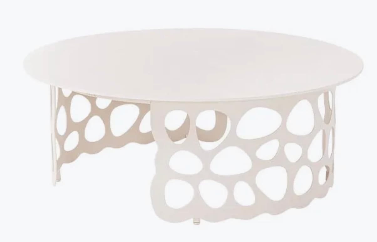 A contemporary, oval-shaped coffee table with a white, matte finish. The tabletop is smooth and circular. The base is a distinctive, openwork design featuring irregular, interconnected voids that create a sculptural and airy aesthetic. The base has a wavy, scalloped bottom edge and stands on small, discreet feet. — 3D model