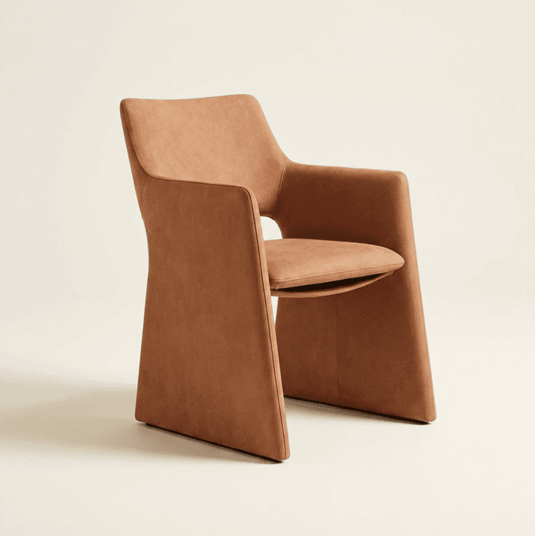 A contemporary armchair with a sculptural, monolithic design, fully upholstered in a smooth, tan-colored material, likely leather or faux leather. The arms and legs are integrated into a single, flowing form, creating a seamless aesthetic. The seat cushion is distinct but fits snugly within the upholstered structure. — 3D model