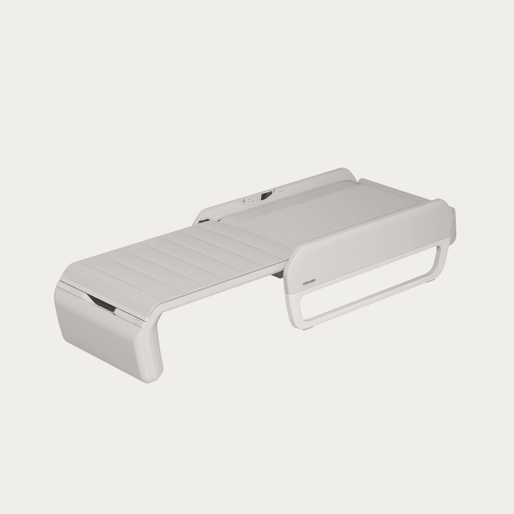 A light grey, sleek automated therapy bed designed for relaxation or therapeutic treatments. It features a segmented, textured lying surface that appears to be foldable or adjustable, supported by a minimalist, molded frame. A control panel is visible at one end, suggesting automated functions. — 3D model