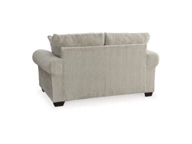 A light greige upholstered loveseat, viewed from the rear-side, featuring rolled arms and two plush back cushions, supported by low-profile dark feet. — 3D model