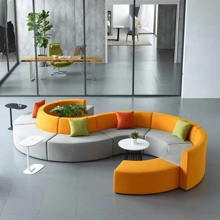 A contemporary modular sectional sofa system arranged in an S-shape, featuring two-tone upholstery in vibrant orange and light grey. The system includes multiple curved seating segments, one central segment with an integrated planter, and is accompanied by two small, distinctively shaped side tables in black and white. Several accent pillows in orange and green are placed on the seating. — 3D model