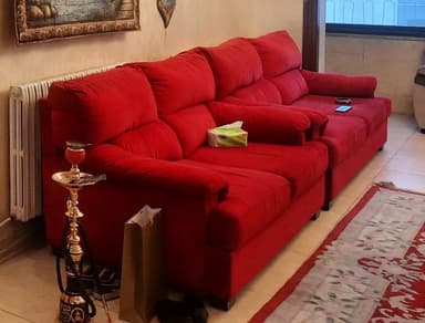 A vibrant red modular sofa, comprising two interconnected sections, designed for comfort. Each section features plush, overstuffed seat and back cushions, along with rounded, generously padded armrests. The sofa is upholstered in a textured red fabric and supported by dark, low-profile block feet, suggesting a contemporary and cozy aesthetic. — 3D model