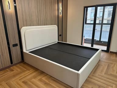A modern platform bed featuring a light-colored upholstered frame and an integrated headboard with soft, rounded corners, designed to support a mattress without the need for a box spring. — 3D model
