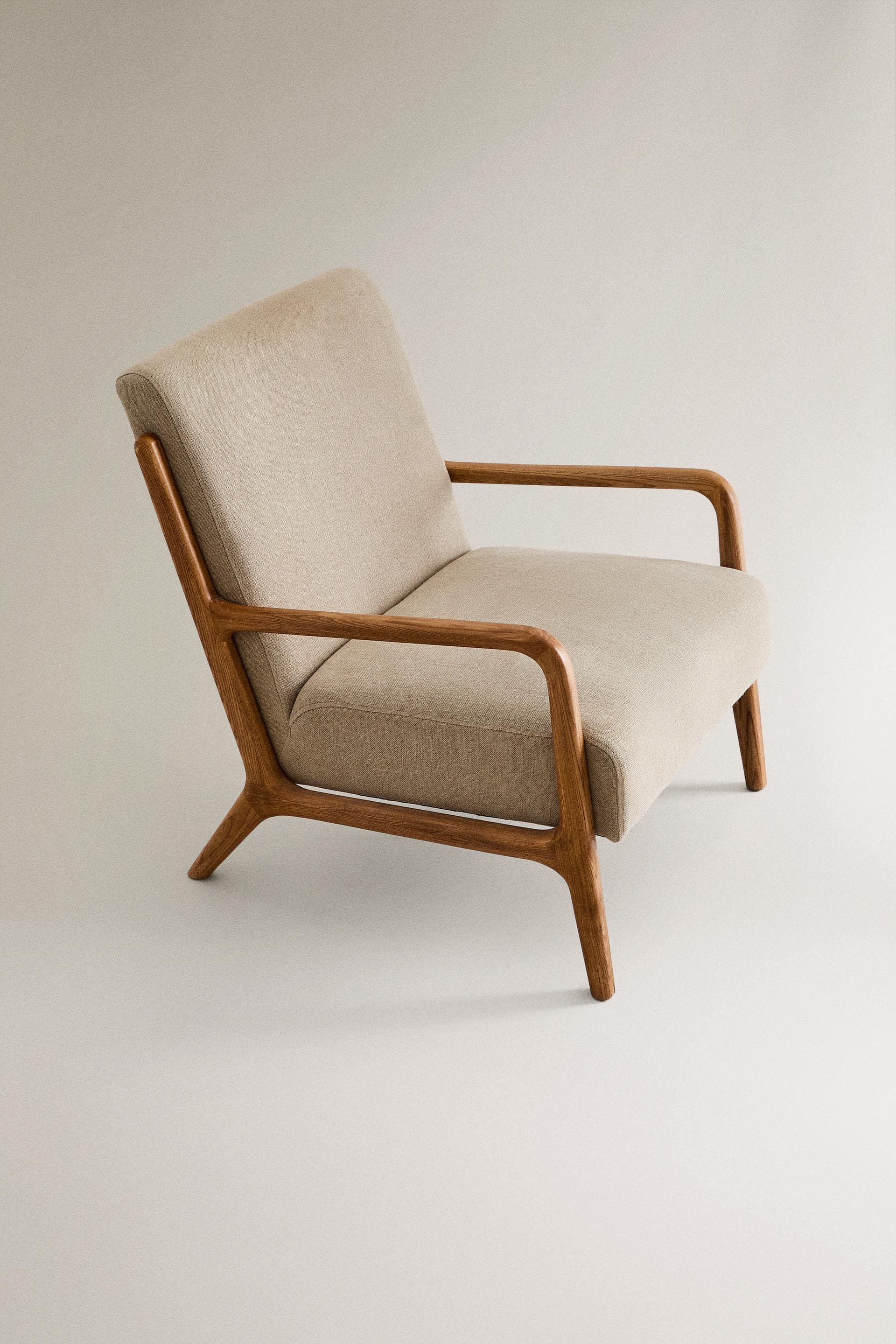 A modern Scandinavian-style lounge chair with an exposed solid wood frame and upholstered cushions. The chair features curved wooden armrests that flow into the front legs, and splayed, tapered rear legs. The seat and backrest are upholstered in a light beige, textured fabric, providing a comfortable and aesthetically pleasing seating option. — 3D model