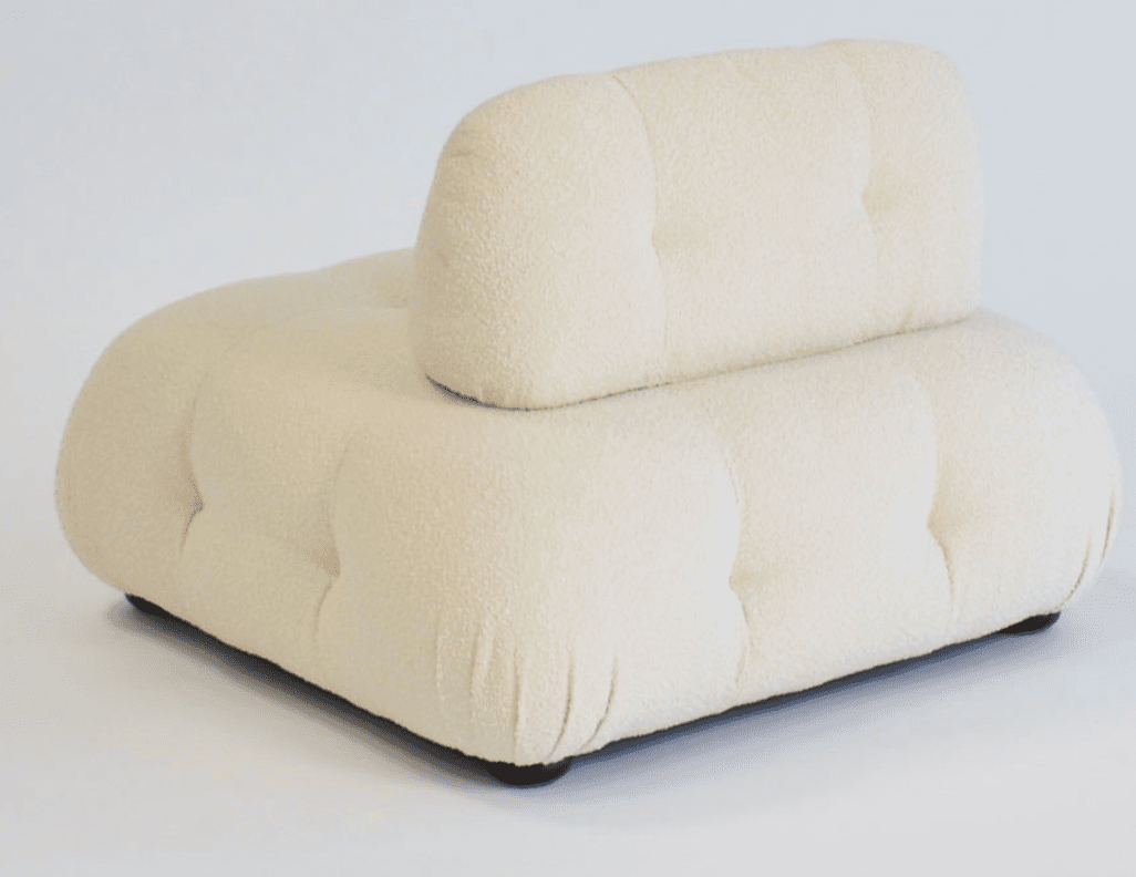 An off-white, deeply tufted, armless modular lounge chair upholstered in a boucle fabric. It features a low-profile design with a separate, equally tufted backrest cushion that appears to rest against the main base. The overall form is soft and rounded, indicative of comfort-focused design. — 3D model