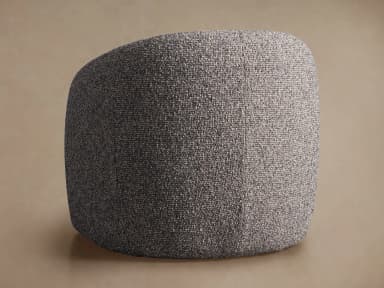 A generously proportioned armchair with a rounded, enveloping silhouette. The chair features a fully upholstered form with a high back that curves around to form integrated armrests. The upholstery has a textured, boucle-like appearance, creating a soft and inviting aesthetic. The base appears to be a continuous, rounded structure that extends to the floor, without visible legs. — 3D model