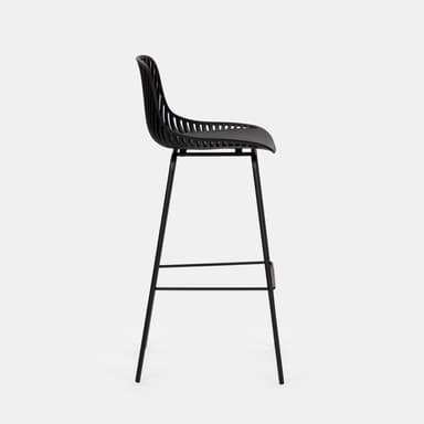 A modern black bar stool with a distinctive design. The seat and backrest are formed by a molded, curved shell with a matte finish, accented by numerous thin, vertical slats that create a semi-transparent effect. The seat itself appears solid and slightly concave for comfort. It is supported by a slender, black metal frame consisting of four legs that are angled outwards for stability, connected by a circular footrest. The overall aesthetic is minimalist and contemporary. — 3D model