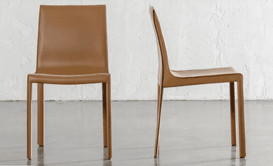 A contemporary armless dining chair featuring a sleek, fully upholstered design in a light brown leather-like material. The chair has a gently curved backrest and four slender, straight legs covered in the same material. — 3D model