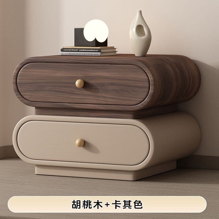 A modern two-drawer nightstand featuring a distinctive rounded and pill-shaped design. The unit comprises two stacked drawers; the upper drawer exhibits a walnut wood grain finish, while the lower drawer is finished in a khaki or light beige color. Both drawers are equipped with small, spherical wooden pull knobs. The overall construction emphasizes smooth, continuous curves, giving it a soft and contemporary aesthetic. — 3D model