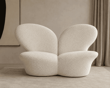 A sculptural, low-profile lounge chair upholstered in cream-colored bouclé fabric. The chair features a distinct organic form with smooth, continuous curves forming the seat, back, and integrated armrests. Its plush appearance suggests comfort, and the overall design is contemporary and minimalist, resting directly on the floor without visible legs. — 3D model